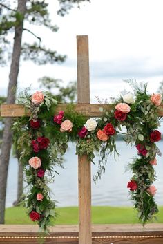 a wooden cross decorated with flowers and greenery