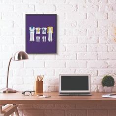 a laptop computer sitting on top of a wooden desk next to a lamp and potted plant