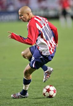 a man kicking a soccer ball on top of a field