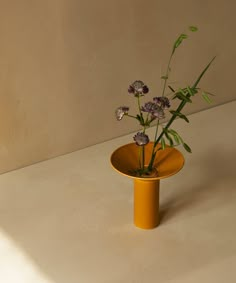 a yellow vase with purple flowers in it