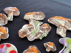 several different types of mushrooms on a black tablecloth with white and red dots around them