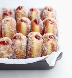 small pastries are covered in powdered sugar and cranberry sauce on a tray