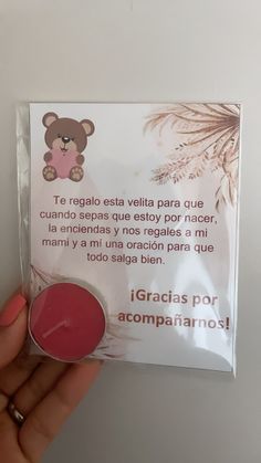 a hand holding a pink lip bale in front of a card with an image of a teddy bear on it