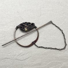 a brooch that is laying on top of a white sheet and has a chain attached to it