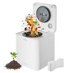 a small white machine with dirt on the ground next to it and a plant growing out of it