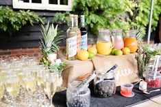 a table topped with lots of glasses filled with liquid and fruit on top of it