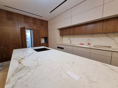 an empty kitchen with marble counter tops and wooden cabinetry on the wall behind it