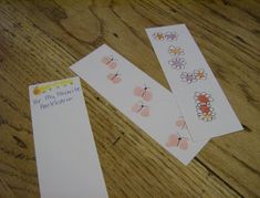 two bookmarks with flowers on them sitting on a wooden table next to an envelope