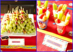 grapes and apples are arranged in cups on a table with place cards for name tags