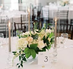 there is a centerpiece with flowers and candles on the table at this wedding reception