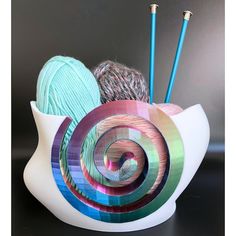 there is a bowl with yarn and knitting needles in it that has been designed to look like a snail