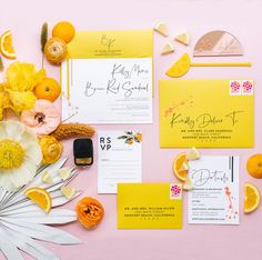 the wedding stationery is laid out with flowers and oranges