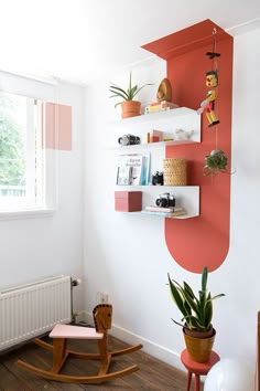 a living room with a rocking chair, bookshelf and potted plants on the wall