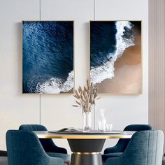 two paintings on the wall above a table with blue chairs