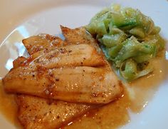 some food is on a white plate with sauce and broccoli in the background