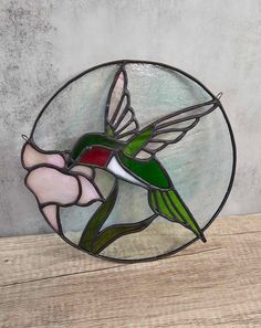 a stained glass hummingbird sitting on top of a wooden table