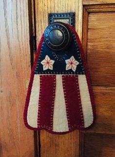 an american flag door hanger hanging on a wooden door with a light switch in the middle