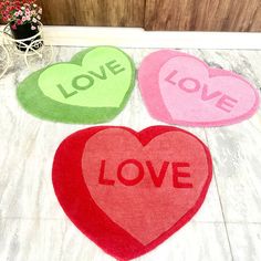 three heart shaped rugs with the word love written on them in red, green and pink