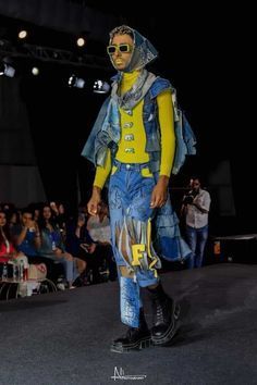 a man in yellow and blue is walking down the runway with his face painted on