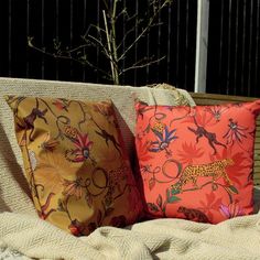 two pillows sitting on top of a couch next to a small tree in the background