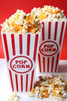 two red and white striped popcorn cups sitting on top of a table