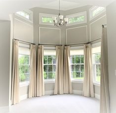 an empty room with three windows and curtains