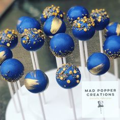 blue cake pops with gold sprinkles are on top of a white plate