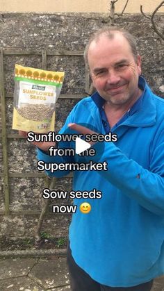 a man holding up a bag of seeds in front of a brick wall with the words sunflower seeds from me supermarket sow seeds now