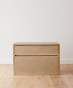 an empty wooden box sitting on top of a hard wood floor next to a white wall