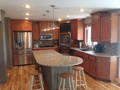 a kitchen with an island and two stools next to the stove top oven in it