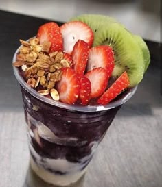 a glass filled with yogurt, strawberries and granola on top of a table