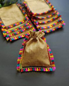 three bags with colorful pom poms are sitting next to each other on a table