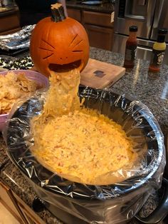 an orange jack - o'- lantern pumpkin sticking out of a bowl of dip