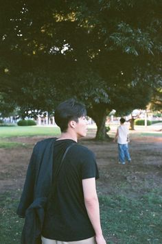 a young man standing in the grass with his back to the camera, looking up