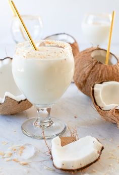 a glass filled with milk next to coconuts