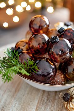 a white bowl filled with lots of different colored glass balls on top of a wooden table