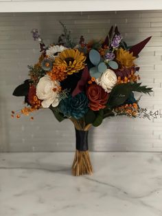 a bouquet of flowers sitting on top of a white marble countertop next to a brick wall