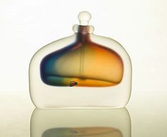 a glass bottle that is sitting on a table with a reflection in the water behind it