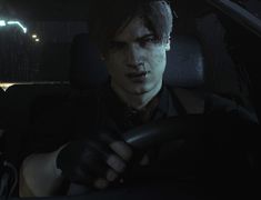 a young man driving in the dark at night with his hand on the steering wheel