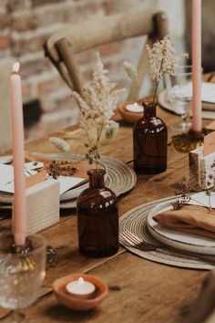 a wooden table topped with plates and vases filled with flowers