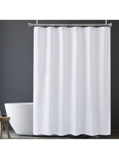 a white shower curtain next to a bathtub in a room with gray walls and wooden floors