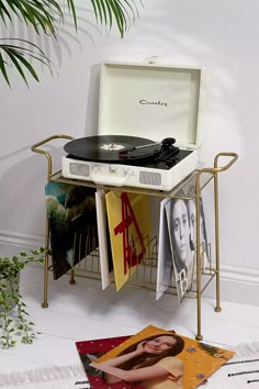 a record player sitting on top of a table next to a potted plant and magazine rack