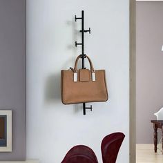 a purse hanging on the wall next to a red chair and table with two chairs