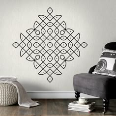 a room with a chair, rug and wall decal that has an intricate design on it