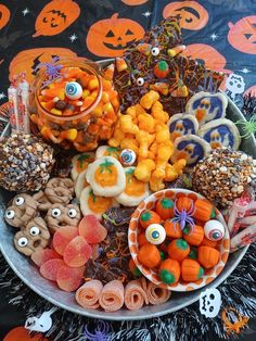 an assortment of halloween treats on a plate with candy eyes and pumpkins in the background