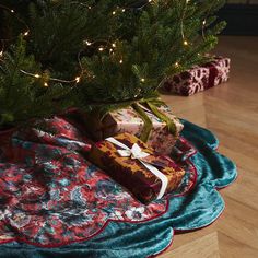 a christmas tree with presents under it on the floor next to a pile of blankets