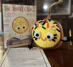 a pumpkin shaped like a cat next to a book and pencils on a table