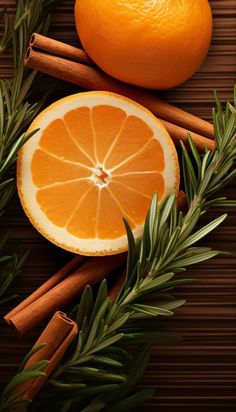 an orange cut in half next to cinnamon sticks and rosemary sprigs on a wooden table