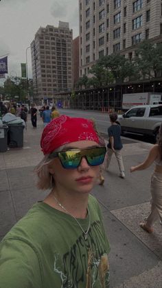 a woman wearing sunglasses and a red hat on the sidewalk in front of some buildings