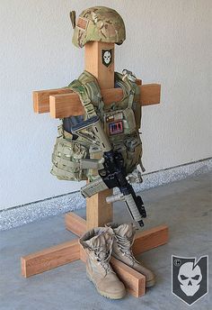 a wooden cross with shoes on it and a soldier's helmet sitting on top